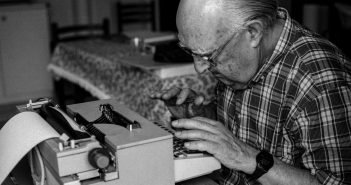 Andrea-Camilleri-alla-macchina-da-scrivere-nella-sua-casa-di-Porto-Empedocle-1999-Ph.-Angelo-Pitrone-scaled.jpg